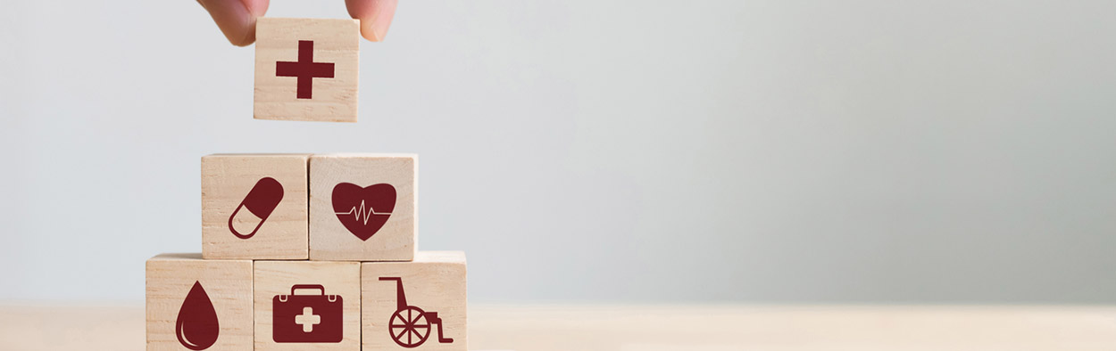 hand building tower of wooden blocks with medical symbols