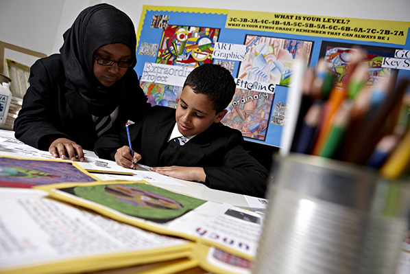 Female teacher assisting primary school pupil with his classwork