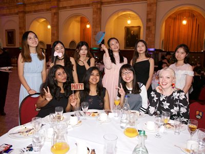 Students posing with photo booth props at formal dinner