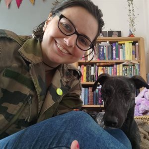 Lauren Walia sitting in front of a bookshelf next to a dog