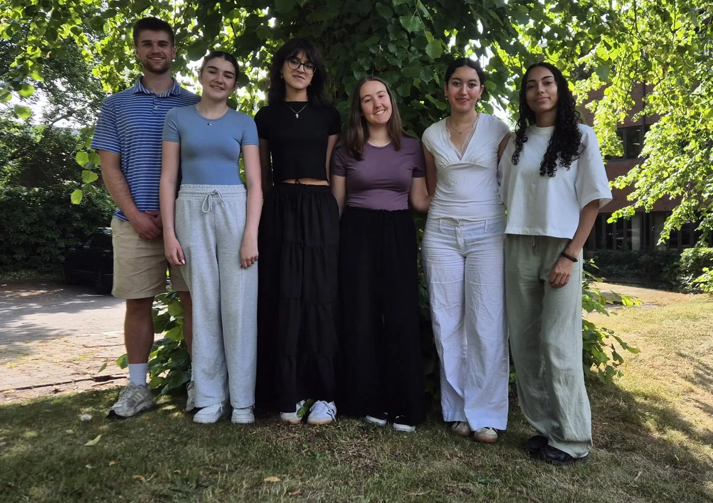 Group of six students standing in front of a tree